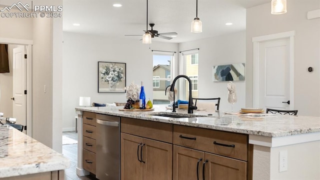 kitchen featuring light stone countertops, stainless steel dishwasher, ceiling fan, and sink