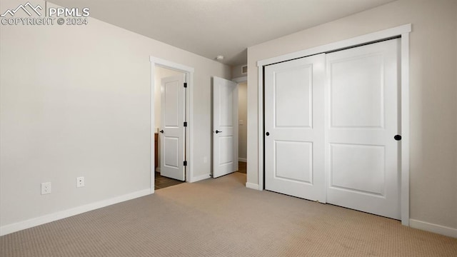 unfurnished bedroom featuring light carpet and a closet