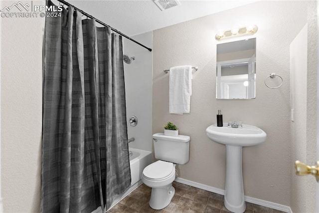 full bathroom featuring sink, shower / tub combo with curtain, and toilet