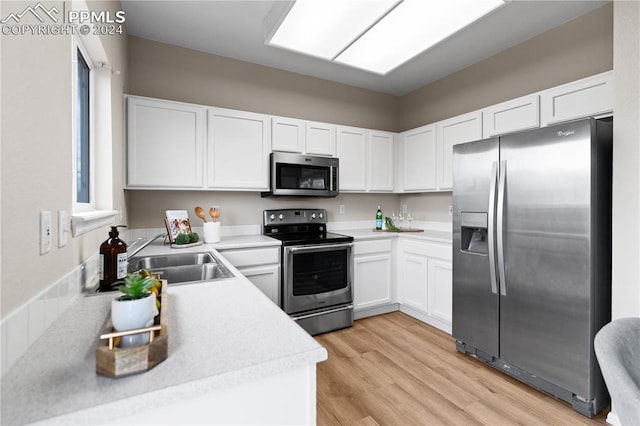 kitchen featuring white cabinetry, sink, stainless steel appliances, and light wood-type flooring