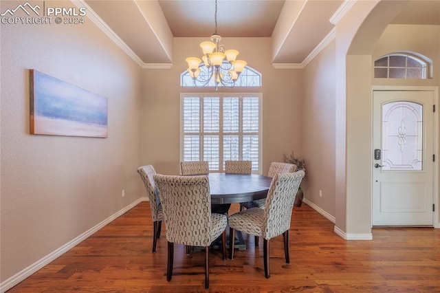 dining room with dark hardwood / wood-style flooring, crown molding, and a notable chandelier