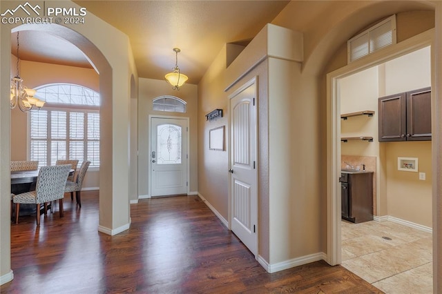 entrance foyer featuring sink, dark wood-type flooring, and an inviting chandelier