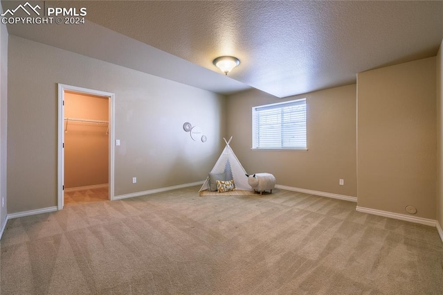 recreation room featuring light carpet and a textured ceiling