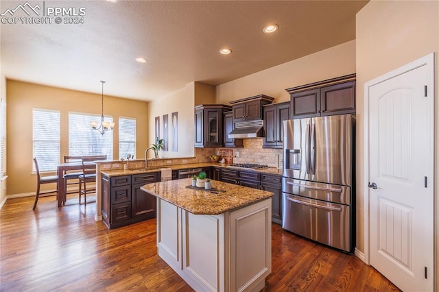 kitchen with kitchen peninsula, dark brown cabinets, hanging light fixtures, and appliances with stainless steel finishes