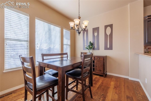 dining area featuring dark wood-type flooring and a chandelier