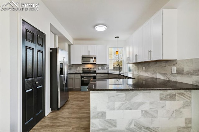 kitchen featuring pendant lighting, kitchen peninsula, sink, and appliances with stainless steel finishes