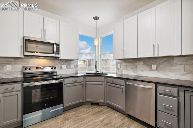 kitchen with stainless steel appliances, sink, white cabinets, gray cabinets, and hanging light fixtures