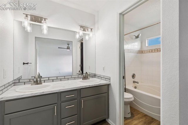 full bathroom featuring vanity, hardwood / wood-style flooring, tiled shower / bath combo, ceiling fan, and toilet