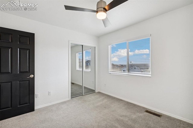 unfurnished bedroom with ceiling fan, light carpet, and a closet