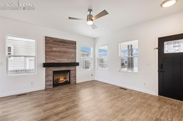 unfurnished living room with a tile fireplace, ceiling fan, and wood-type flooring