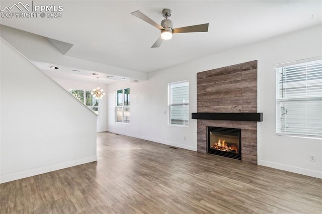 unfurnished living room with ceiling fan with notable chandelier and hardwood / wood-style flooring