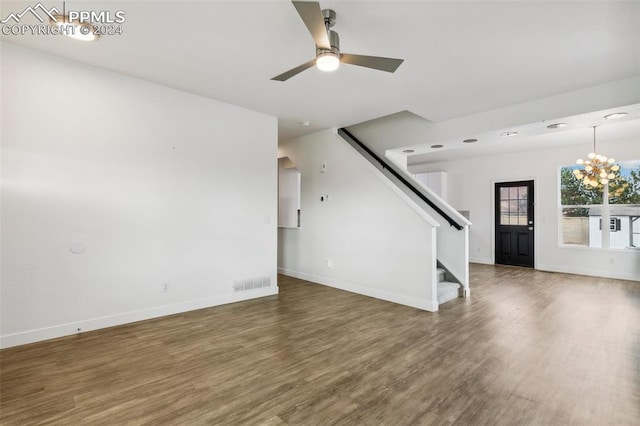 unfurnished living room with dark hardwood / wood-style flooring and ceiling fan with notable chandelier