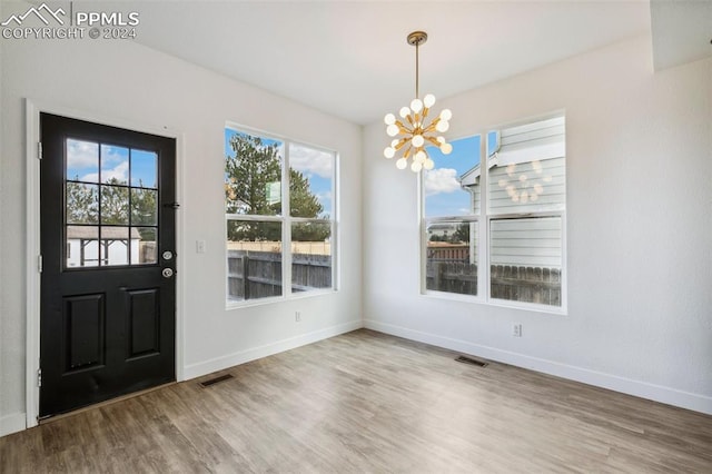 entrance foyer with hardwood / wood-style floors and an inviting chandelier