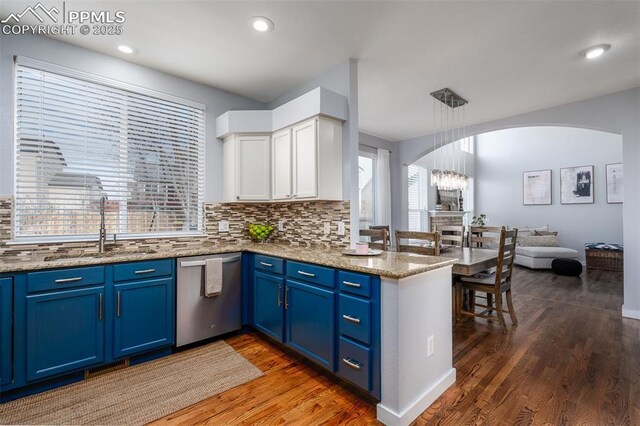 kitchen with stainless steel dishwasher, blue cabinets, sink, white cabinets, and hanging light fixtures