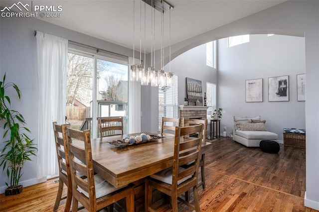 dining space featuring hardwood / wood-style flooring, a notable chandelier, and a fireplace