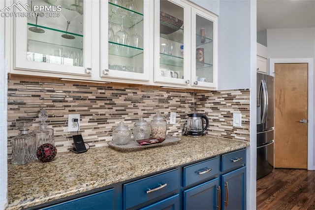 bar featuring white cabinets, decorative backsplash, stainless steel fridge with ice dispenser, and blue cabinetry