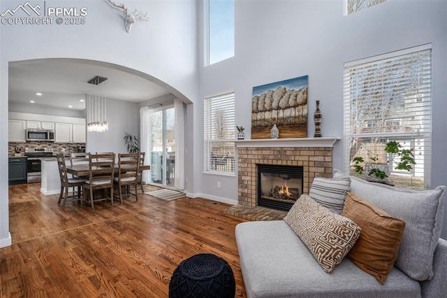 living room featuring a fireplace, a high ceiling, and dark wood-type flooring