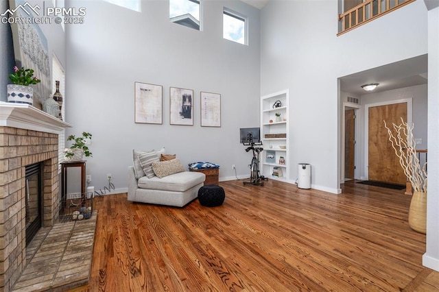 living room featuring a fireplace, a high ceiling, and wood-type flooring