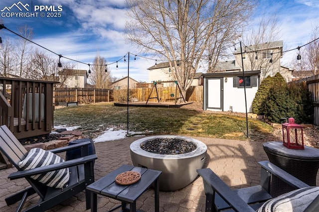 view of patio / terrace featuring a playground, a fire pit, and a storage shed