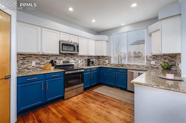 kitchen with white cabinets, sink, blue cabinetry, and stainless steel appliances