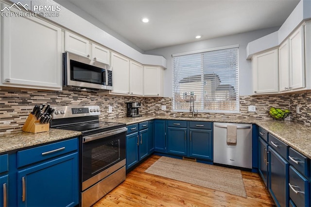 kitchen featuring white cabinetry, sink, stainless steel appliances, light stone counters, and blue cabinets