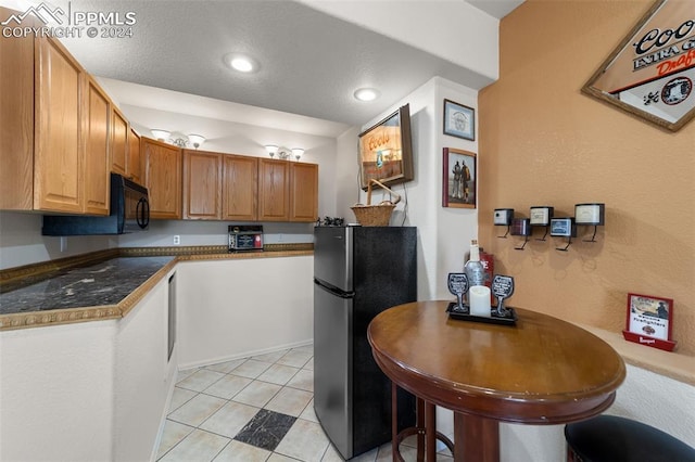 kitchen featuring light tile patterned floors and stainless steel refrigerator