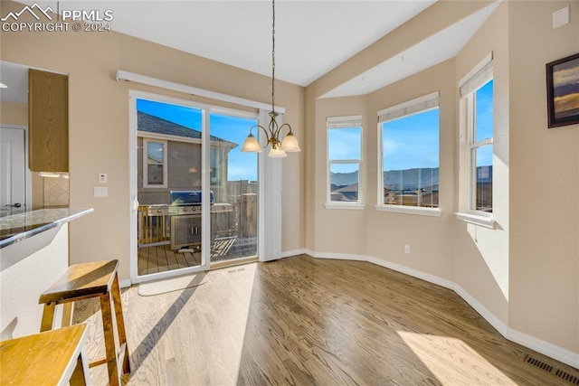 unfurnished dining area with hardwood / wood-style floors and an inviting chandelier