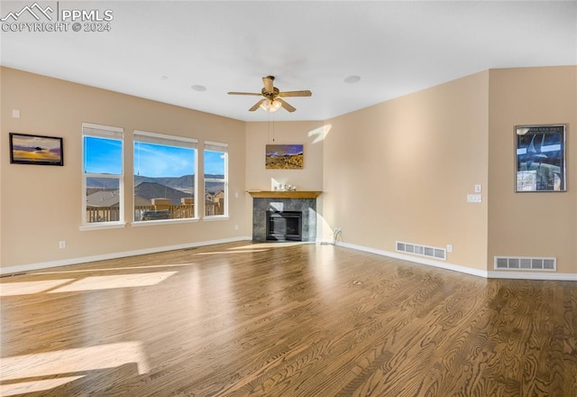 unfurnished living room with a high end fireplace, hardwood / wood-style floors, and ceiling fan