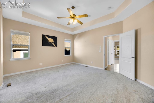 carpeted empty room featuring a tray ceiling and ceiling fan