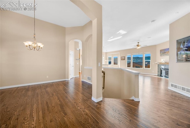 empty room featuring ceiling fan with notable chandelier and dark hardwood / wood-style floors