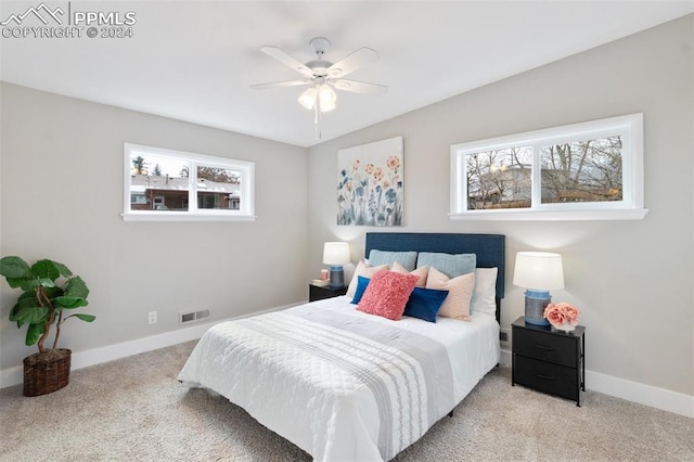 bedroom featuring multiple windows, ceiling fan, and light colored carpet