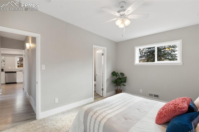 bedroom featuring ensuite bathroom, ceiling fan, light hardwood / wood-style flooring, and vaulted ceiling