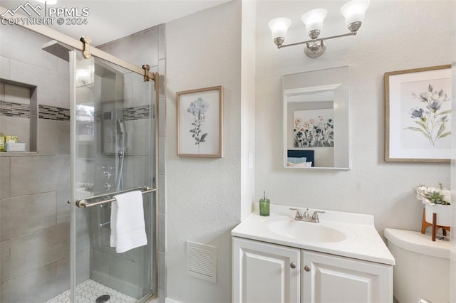 bathroom with vanity, toilet, and a shower with shower door