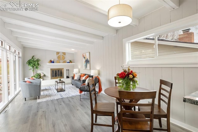 dining area with hardwood / wood-style flooring, beamed ceiling, and wooden walls