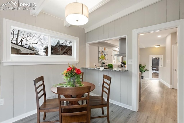 dining space with beam ceiling and light hardwood / wood-style floors