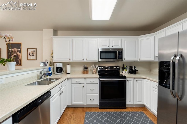 kitchen with sink, white cabinets, stainless steel appliances, and light hardwood / wood-style flooring