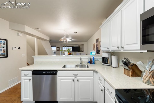 kitchen with white cabinets, sink, hardwood / wood-style flooring, appliances with stainless steel finishes, and kitchen peninsula