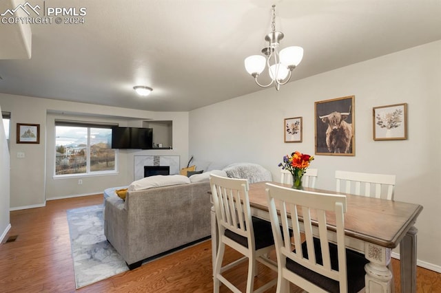 dining area featuring a fireplace, a chandelier, and hardwood / wood-style flooring