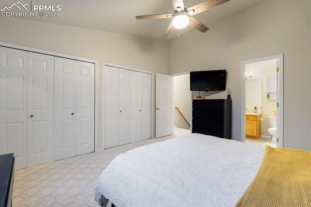 carpeted bedroom with two closets, ensuite bathroom, high vaulted ceiling, and ceiling fan