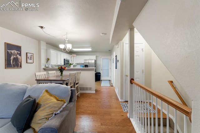 hallway featuring a chandelier and light hardwood / wood-style flooring