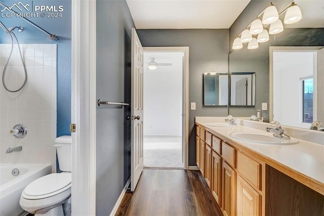 full bathroom featuring vanity, hardwood / wood-style floors, tiled shower / bath combo, and toilet