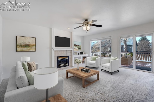 living room featuring a tile fireplace, light colored carpet, and ceiling fan