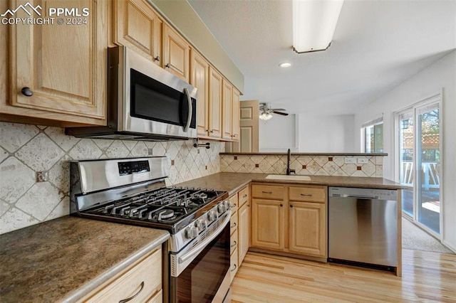 kitchen featuring ceiling fan, sink, light hardwood / wood-style flooring, decorative backsplash, and appliances with stainless steel finishes