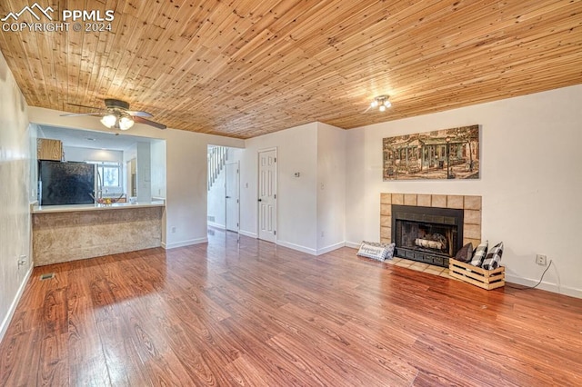 unfurnished living room with a fireplace, wood-type flooring, ceiling fan, and wooden ceiling