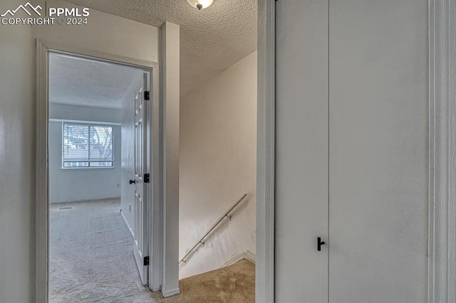 hallway featuring light colored carpet and a textured ceiling