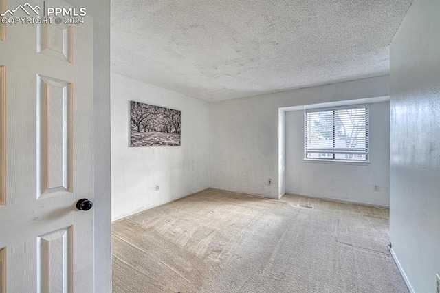 carpeted empty room featuring a textured ceiling