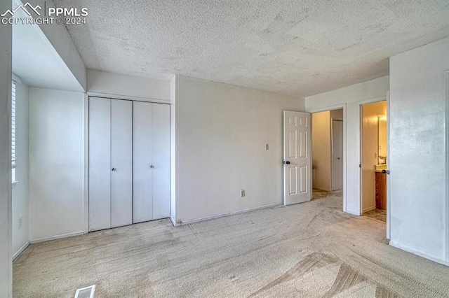 unfurnished bedroom with a textured ceiling, light colored carpet, and a closet