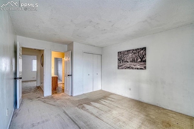 unfurnished bedroom with carpet, a textured ceiling, and a closet