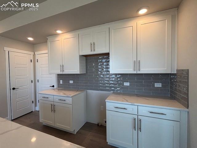 kitchen featuring dark wood-type flooring, white cabinets, light stone counters, and tasteful backsplash