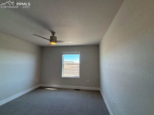 unfurnished room with ceiling fan, dark carpet, and baseboards